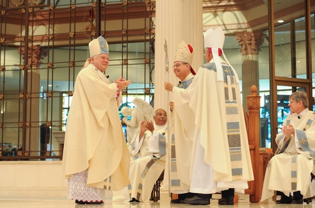 Archbishop Thomas Wenski applauds along with the congregation after Bishop Estevez receives the crozier symbolizing his authority as bishop of St. Augustine.