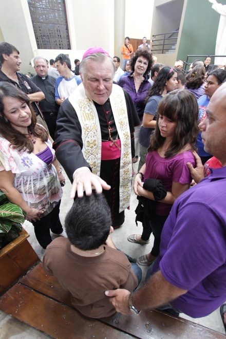 Archbishop Thomas Wenski blesses 16-year-old Ricardo Silva, seated, and his parents, members of St. Catherine of Siena Parish in Miami, before their departure for World Youth Day.