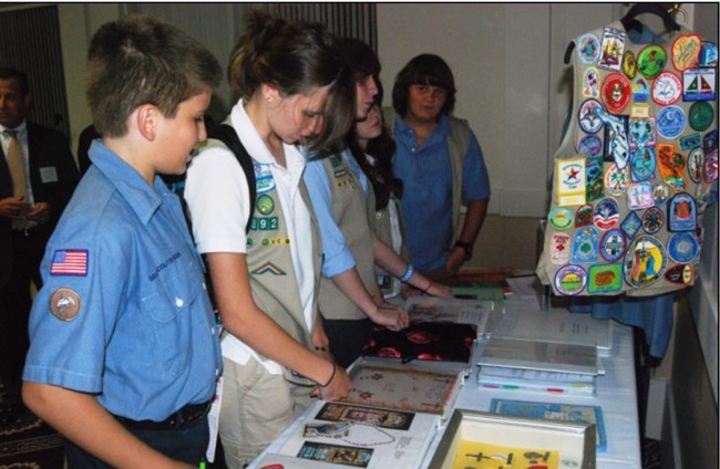 Scouts reviewing Catholic Scouting material, including Awards, Emblems, workbooks, and service projects.