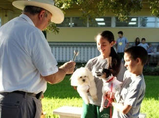 Father Jesus Saldaa, pastor of St. Kevin Parish, blesses the dogs of students, Nicole and Duval Rodriguez.