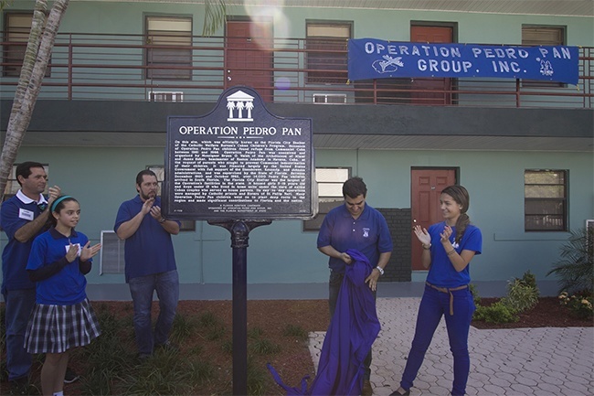 Representatives of the second and third generations of Pedro Pan unveil the Florida Heritage Landmark in the front of the Florida City apartment building that housed many Pedro Pans in the early 1960s. From left: Diego R. del Pino, his daughter, Paloma del Pino and Eric del Pino, son, granddaughter and son of Florida City alumnus Carmen Valdivia; and Daniel E. Romanach and Raquel Aveillez, son and granddaughter of Operation Pedro Pan Group's president, Carmencita Romaach.