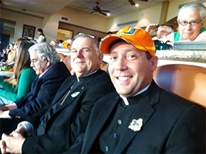 Archbishop  Thomas Wenski attends the University of Miami versus Virginia Tech game at SunLife Stadium, along with his priest-secretary, Father Richard Vigoa.