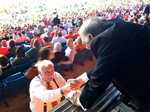 Archbishop Wenski shakes hands with a legendary Hurricanes coach, Howard Schnellenberger.