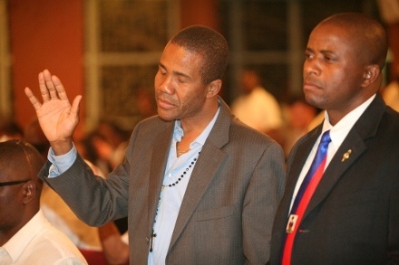 Hans Chardy raises his hand in memory of those who died in the Haitian earthquake. North Miami Mayor Andre Pierre is standing next to him.