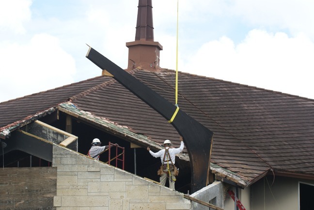 The old, damaged structural beam is removed from the roof of St. Catherine of Siena Church.