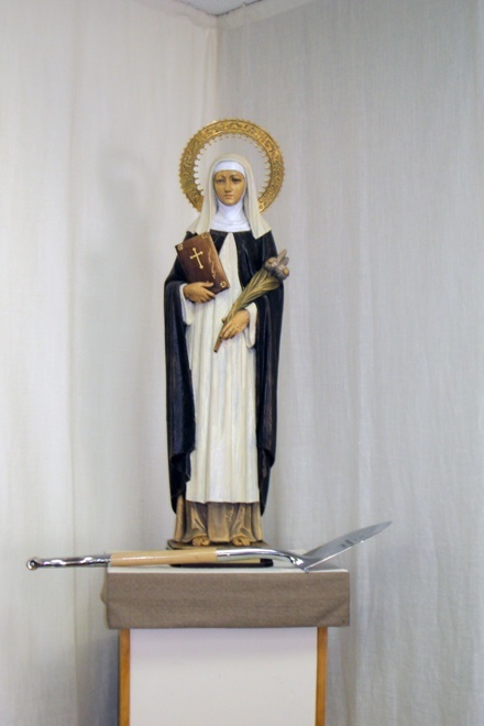 A Silver Shovel, symbol of the ministry group that is working toward the restoration of St. Catherine of Siena Church, sits at the foot of a statue of the parish's patron saint.