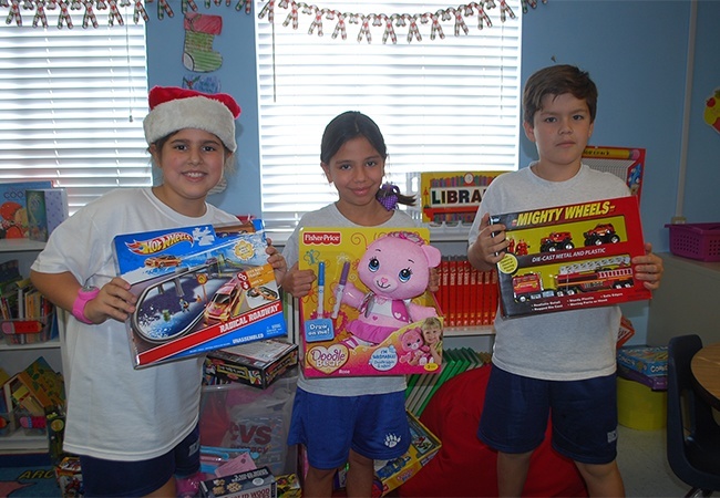 From left: St. Agnes third graders Isabella Carballo, Isabella Andrade and Lucas Bayas show off some of the toys they collected.