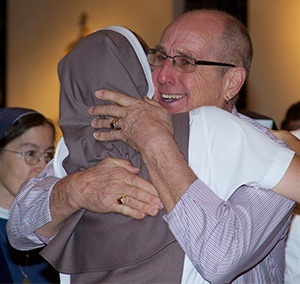 Richard Voss, godfather to Sister Clara Maria, hugs her after she received the signs of profession: habit, veil and crucifix.