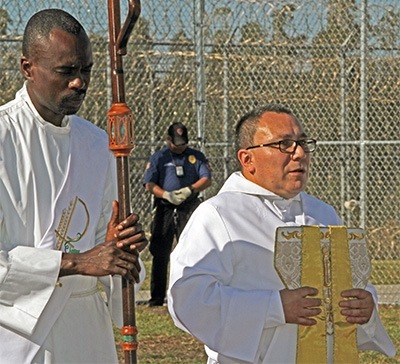 Deacon Alpha Fleurimond, left, and Deacon Edgardo Farias hold the archbishop's staff and miter during the Mass.