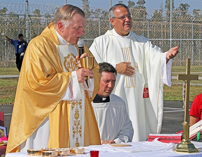 Archbishop Thomas Wenski celebrates the Mass with Father Jesus Arias, right, pastor of Good Shepherd Church in Miami. His master of ceremonies, Father Richard Vigoa, can be seen kneeling during the consecration.