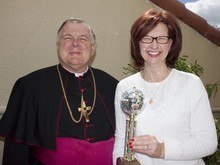 Popular vote winner Cheryl Whapham of the lay ministry office poses with her mirrorball trophy and Archbishop Thomas Wenski upon her return to work March 5.