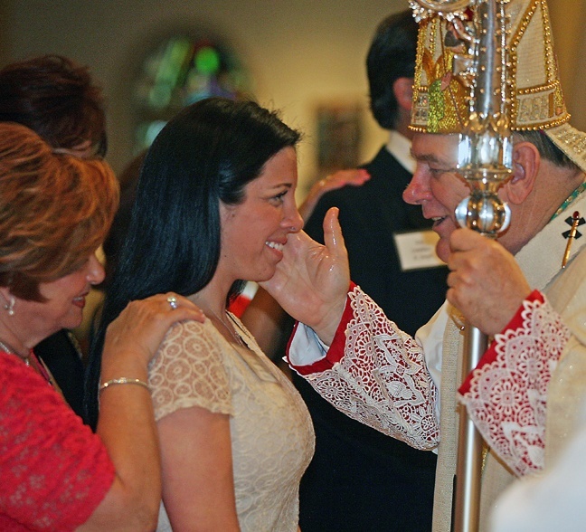 A woman is confirmed by Archbishop Thomas Wenski during the Rite of Reception Mass April 29.