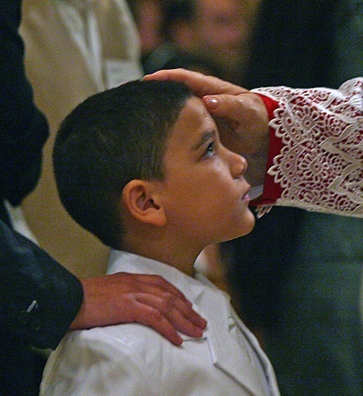 While receiving the sacrament of Confirmation, Anthony Arteda, 6, looks up at Archbishop Thomas Wenski as he anoints him.