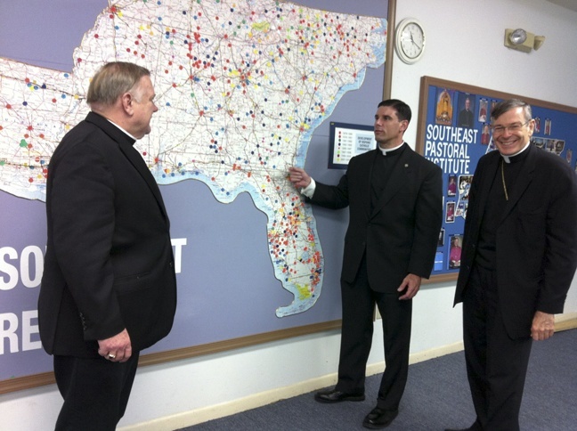 Piarist Father Rafael Capo, center, points to a map of the region where the SouthEast Pastoral Institute provides programs to develop Hispanic ministries and Hispanic Church leaders. With him are two of Florida's bishops, Archbishop Thomas Wenski of Miami and Bishop Gerald Barbarito of Palm Beach.