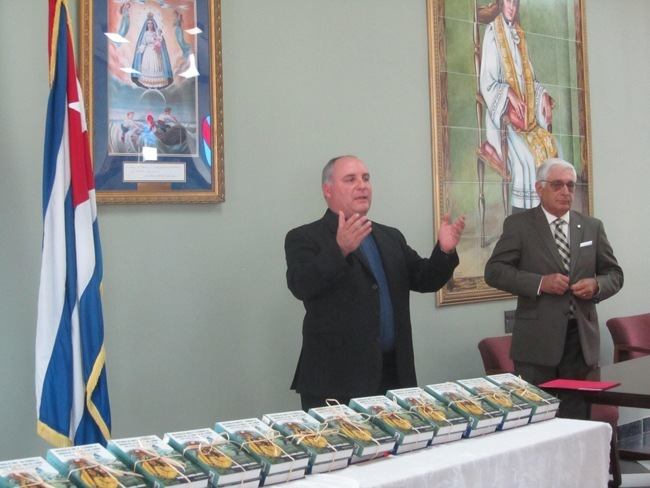 El Padre Juan Rumin Dominguez, rector de la Ermita de la Caridad, bendice los libros sobre la Virgen de la Caridad antes de repartirselos a representantes de escuelas catolicas y del sistema bibliotecario publico del condado Miami-Dade. A la derecha esta el autor e historiador Salvador Larrua-Guedes.