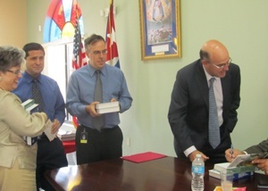 Dave Masters y Nelson Bonet, profesores de Msgr. Edward Pace High School en Miami Gardens, esperan para que el autor firme su copia de los dos tomos del libro, mientras Hope Sadowski del Departamento de Escuelas de la Arquidiocesis, se rie.