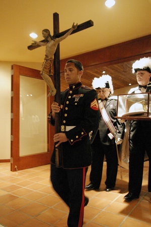 Corporal Luque Barrientos of the U.S. Marine Corps, a 2003 graduate of St. Rose of Lima School in Miami Shores, carries the processional cross into the Mass, followed by members of the Knights of Columbus carrying the helmet worn by N.Y. Fire Department chaplain Father Mychal Judge, the Franciscan priest who was among the first to die on 9/11.