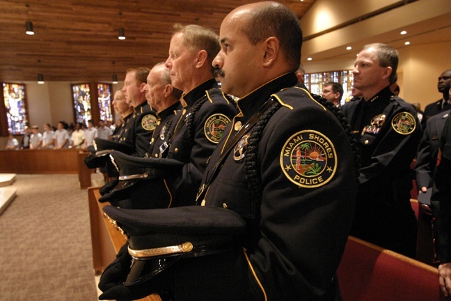 Members of the Miami Shores Police Department Honor Guard sit in the front pew of St. Martha Church during the Mass.