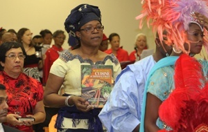 Thelma Okafor, representing Africa, carries a Trinidad and Tobago cookbook as part of the offertory. Representatives of France, Spain, China, East India, and Carib and Arawak Indians carried offertory gifts to represent the cosmopolitan nature of the island nation.