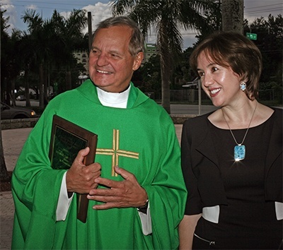 Msgr. Franklyn Casale, holding his award, and St. Thomas University Professor Roza Pati, director of the Human Trafficking Academy and executive director of the Intercultural Human Rights graduate program, talk to well-wishers after the Mass.