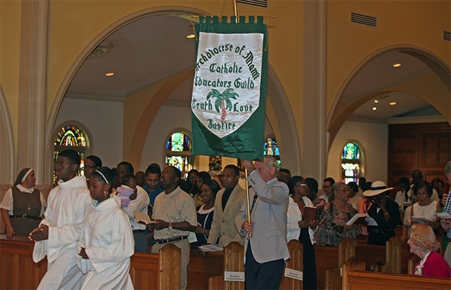 Catholic Educators Guild member Richard Deaguero carries the group's banner into church.