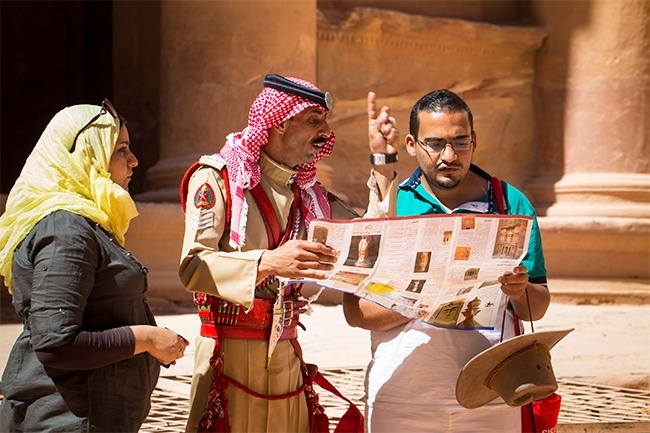 A Bedouin military man on duty at Jordans Petra guides tourists near the sites famous Treasury building, carved into the side of a rock and seen in one of the Raiders of the Lost Ark films as the mythical location of the holy grail. The caves, however, were mostly burial sites of the Nabataean people.