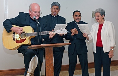 Father Federico Capdepon, St. Martha's former pastor, Father Jets Medina, former parishioner, Father Wilfredo Contreras, current administrator, and Dominican Sister Mary Tindel, parish music director, sing "This Land is Your Land, This Land is My Land" at farewell dinner for Father Jude.