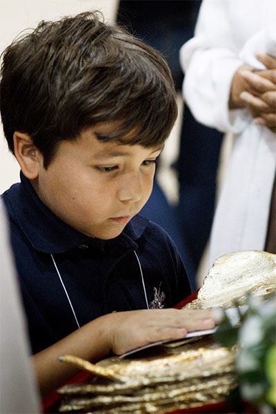 A Catholic school student venerates a relic of Pope John Paul II Nov. 5 as part of a youth rally in honor of the future saint at St. Thomas University in Miami.