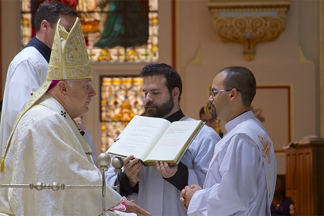 Emilio Travieso kneels before Archbishop Thomas Wenski during the Rite of Ordination at the historic Gesu Church in downtown Miami.