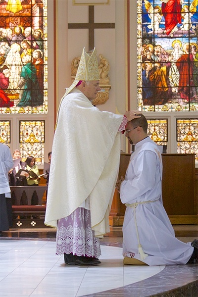 Archbishop Thomas Wenski lays hands on Emilio Travieso, calling down the Holy Spirit and ordaining him a priest.