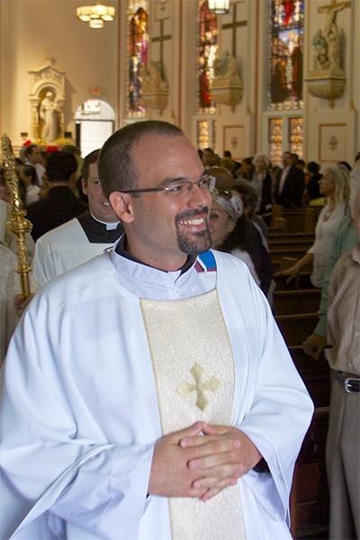 Newly ordained Jesuit Father Emilio Travieso smiles as he processes out of Gesu church at the conclusion of his ordination Mass.