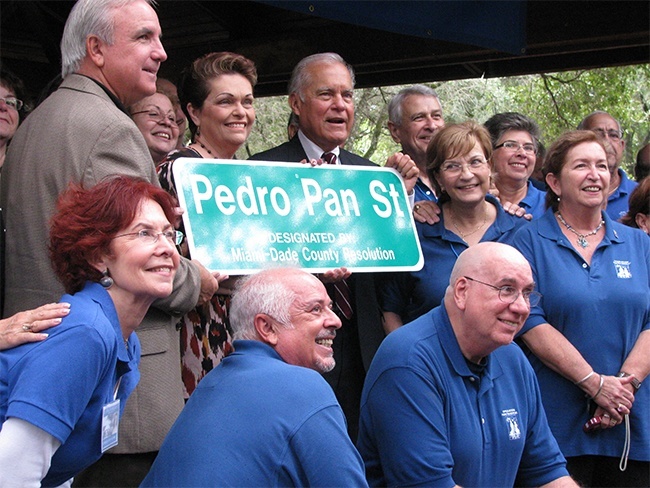 Miami-Dade Mayor Carlos Gimenez,  Commissioner Rebeca Sosa and Commissioner Javier Souto hold the Pedro Pan Street plaque surrounded by former Pedro Pan children.