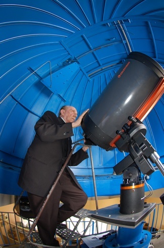 Jesuit Father Pedro Cartaya poses by the telescope inside the Fr. Benito Vines, SJ Observatory at Belen Jesuit Prep.