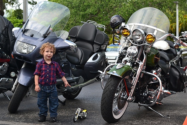 Andrew Diaz, a young member of Our Lady of the Holy Rosary-St Richard Parish, shows off his bike, parked alongside the big ones.