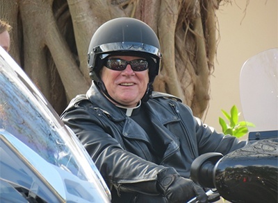 Archbishop Thomas Wenski on his motorcycle, smiling and anticipating the official start of the poker run, right after celebrating Mass at Our Lady of the Holy Rosary-St Richard Church.