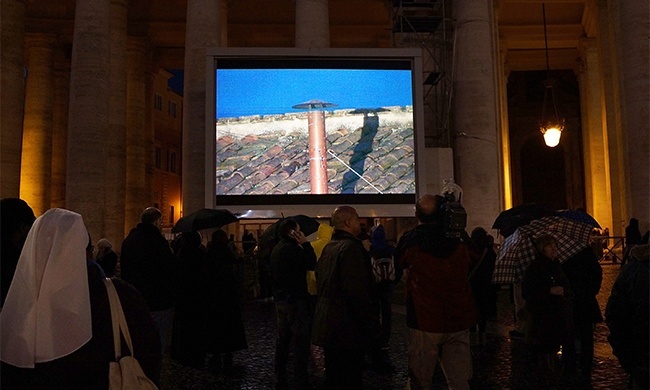 Hundreds of people watch a TV screen as they wait for a sign of smoke in St. Peter's Square on March 12, 2013 in Vatican City, Vatican. Pope Benedict XVI's successor is being chosen by the College of Cardinals in Conclave in the Sistine Chapel. The 115 cardinal-electors, meeting in strict secrecy, will need to reach a two-thirds-plus-one vote majority to elect the 266th Pontiff.