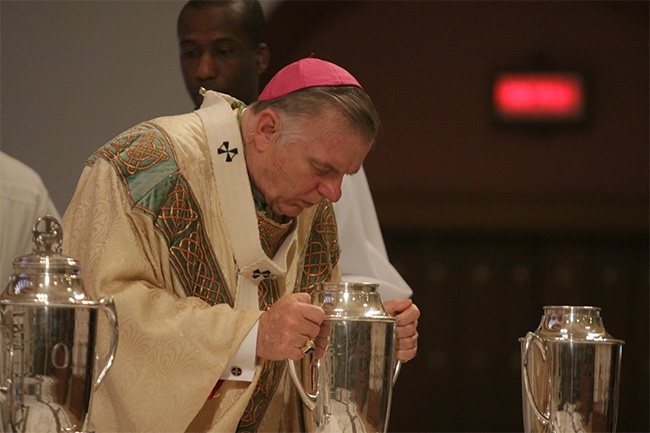 Archbishop Thomas Wenski blesses the Oil of Chrism by blowing on it.