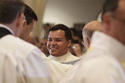 A newly-ordained Father Elvis Gonzalez reacts with joy after being vested.