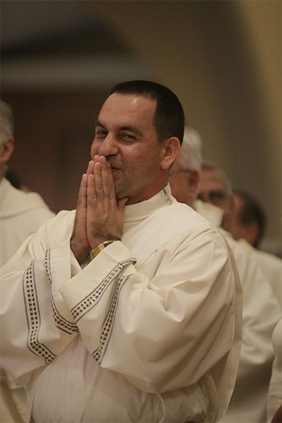 Deacon Carlos Cabrera smiles as archdiocesan priests process past him at the start of the Mass.