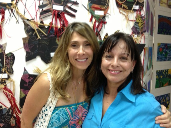 Art teachers Vivian Macia and Wilma De Voe pose for a photo in front of some of their students' artwork.