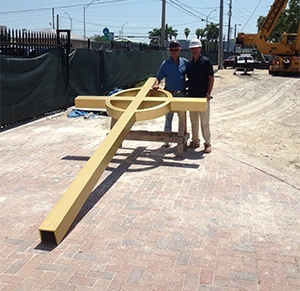 Members of GSD Construction Co. pose with the cross that will stand atop the new Notre Dame d'Haiti church.