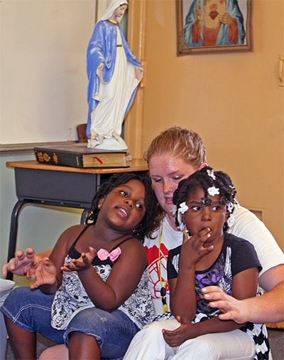 Peoria Notre Dame High School student Monica Voudre, 16, holds Harmony Beutus, 5, and Anastasia Pierre, 5, as they listen to a Dr. Seuss story, "Horton Hatches an Egg."