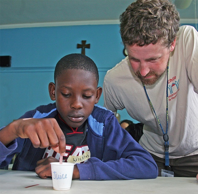 John Donnelly, Spanish and religion teacher at Peoria Notre Dame High School, helps Wilkins Germine, 10, with a science project using litmus paper to test for acids and bases.