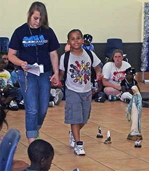 Ambrosia Walter, 14, and Ismael Pina, 8, recite the rosary as they walk around a statue of the Virgin Mary. They were one of three duos that took turns leading the recitation during the Mary and the Saints summer camp.