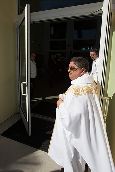 Father Enrique Delgado, St. Katharine Drexel's pastor, ceremonially opens the door at the start of the dedication Mass.