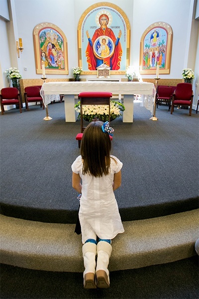 A youngster pauses for private prayer at the altar of St. Katharine Drexel Church following the Mass of dedication.