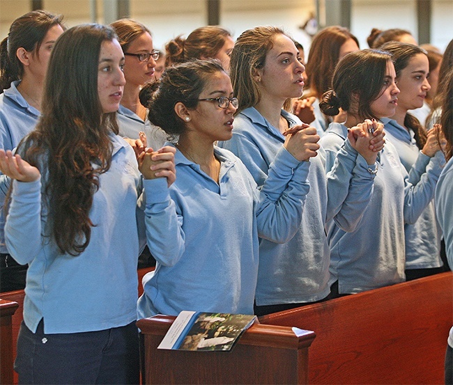 Our Lady of Lourdes seniors Sofia McGraw,17, Natalia Martinez, 17, and Diana Martinez, 18, join hands to pray the Our Father during Mass.