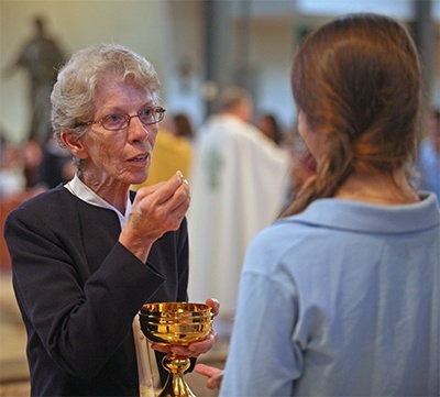 Lourdes Academy's principal, Sister Kathryn Donze, distributes Communion to freshman students during the Mass.