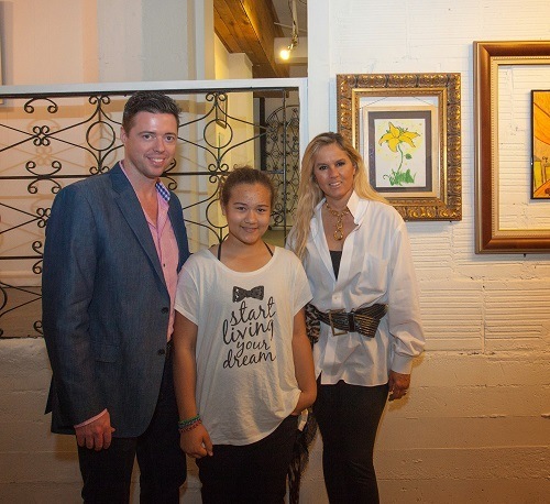 Samara Gustafson, from the Brother Rice Honors Academy at Archbishop Curley Notre Dame, stands in front of her work, Flowers Gleam and Glow, with Elvira Aeda Dago, curator, McCormick Place, and Sean McCormick, owner, McCormick Place.