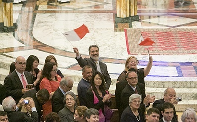 Bishop Peter Baldacchino's sister, Paula Muscat, and his brother, John, wave the flag of Malta as he walks through the church giving his first blessing to the congregation.